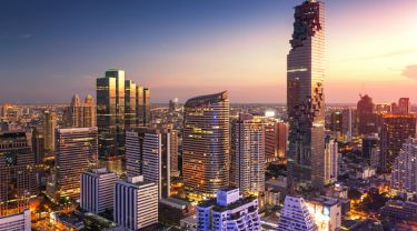Aerial view of downtown Bangkok with skyscrapers and condominiums at sunset.