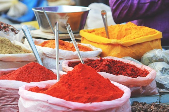 Cloth bags of colourful spices sit in a marketplace.
