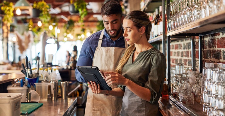 Restauranteurs discuss deliveries while standing behind their beautiful bar.