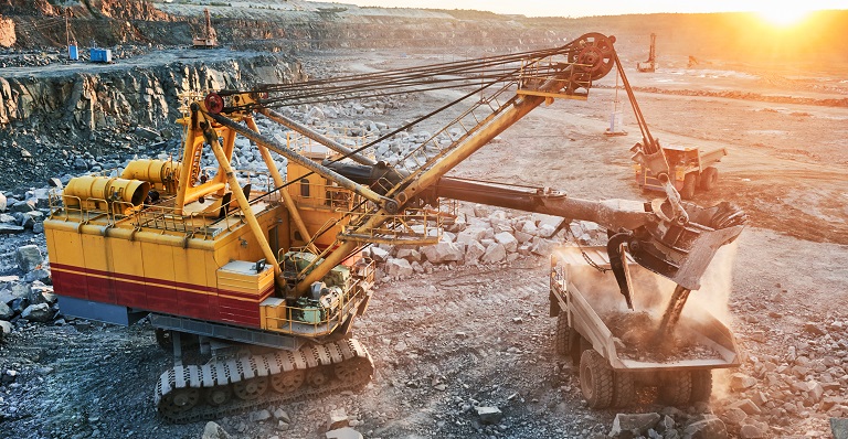 Mining excavator loading granite into dump at quarry.