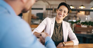A confident and smiling woman is shaking hand with another person