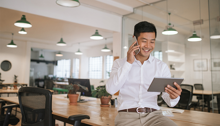Businessman talking to an export advisor on the phone and looking at company information on his tablet