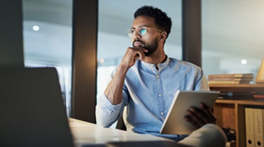 A serious-looking man gazes pensively at his lap-top.