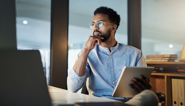 A serious-looking man gazes pensively at his lap-top.