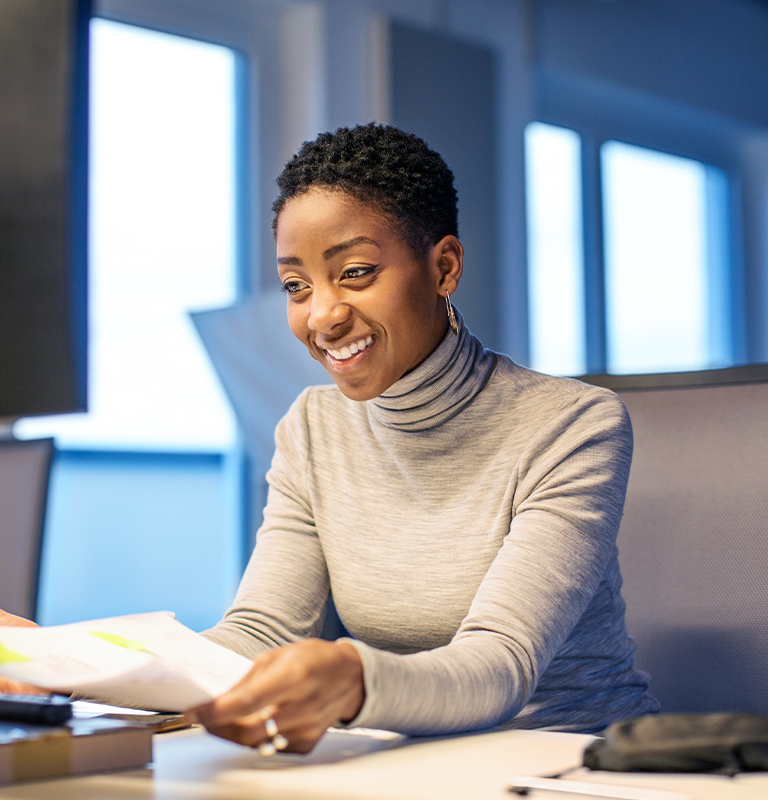 A  business woman sitting at her desk is talking during a conference call.