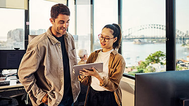 Two business professionals planning for global market expansion, looking at a laptop in an office.