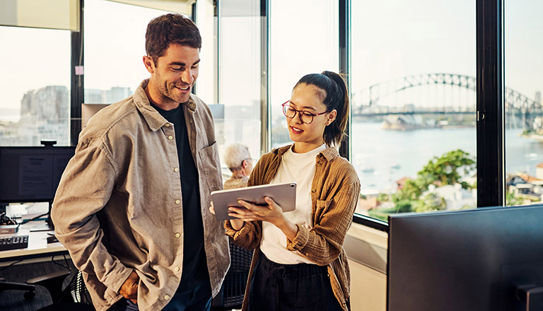 Two business professionals planning for global market expansion, looking at a laptop in an office.