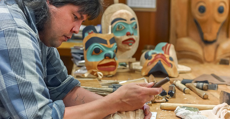 An indigenous mask carver working in his shop.