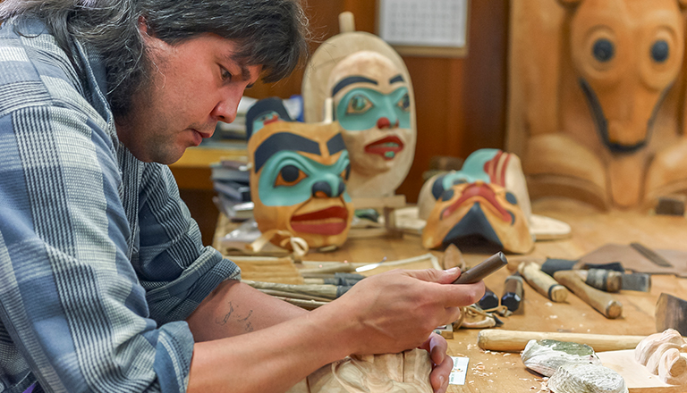 An indigenous mask carver working in his shop.