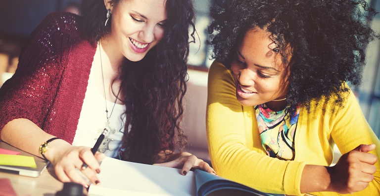 Two smiling women reading a report