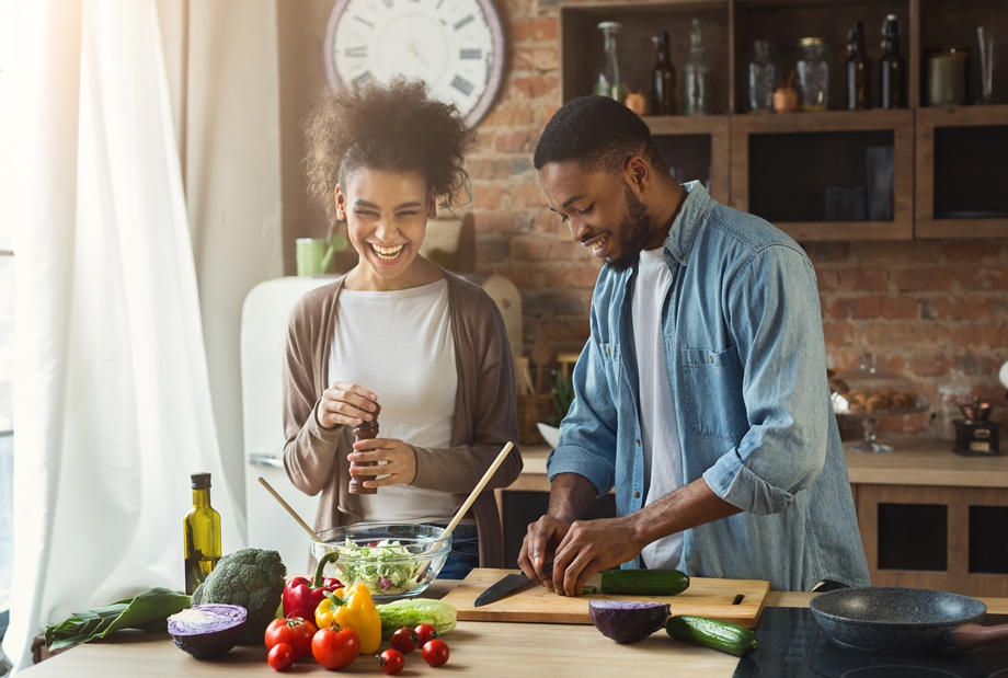 Young Black couple enjoy preparing salad together in their kitchen
