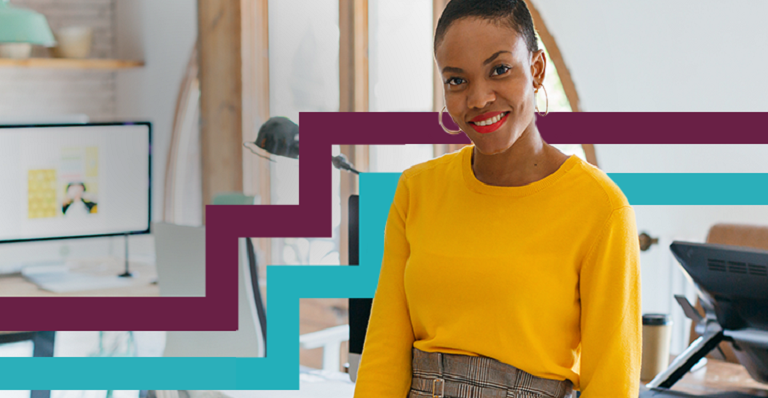 Diverse woman sitting on desk looking directly at camera.