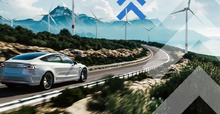 Une voiture électrique roule sur une route bordée d’éoliennes, avec des montagnes à l’horizon.