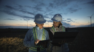 Image of female engineers discussing implementation of wind turbines on farm.