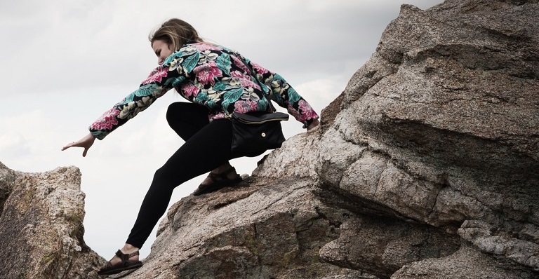 Une randonneuse fait une manœuvre risquée pendant son ascension entre deux rochers.