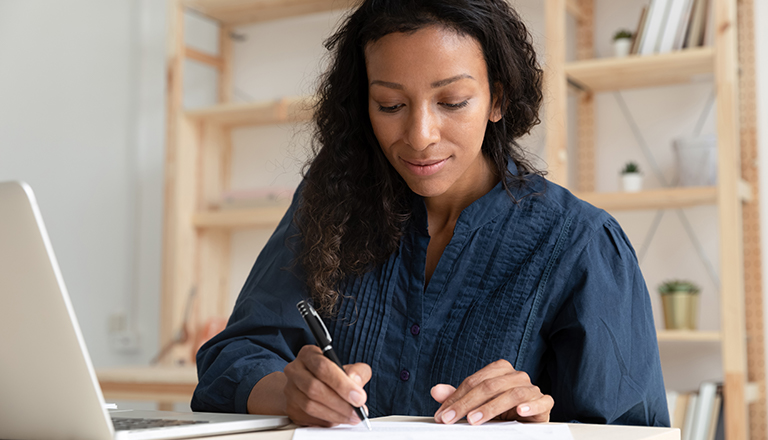 A business woman is working at her desk reviewing business documents.