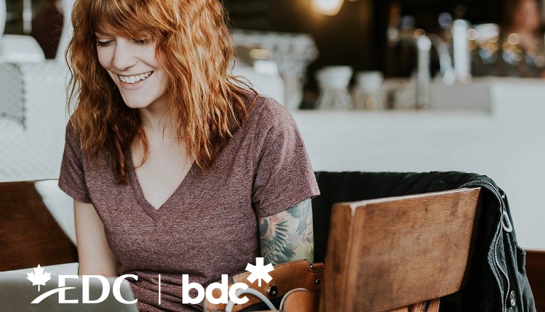 A young business owner in a cafe sells online using her laptop.